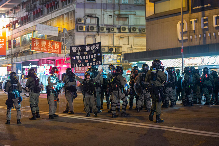 Hong Kong police holding a "warning: tear smoke" sign
